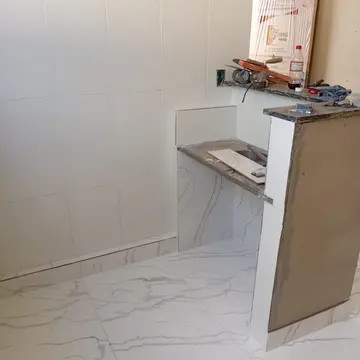 Bancadas em granito esculpido e paredes revestidas integradas a instalações embutidas